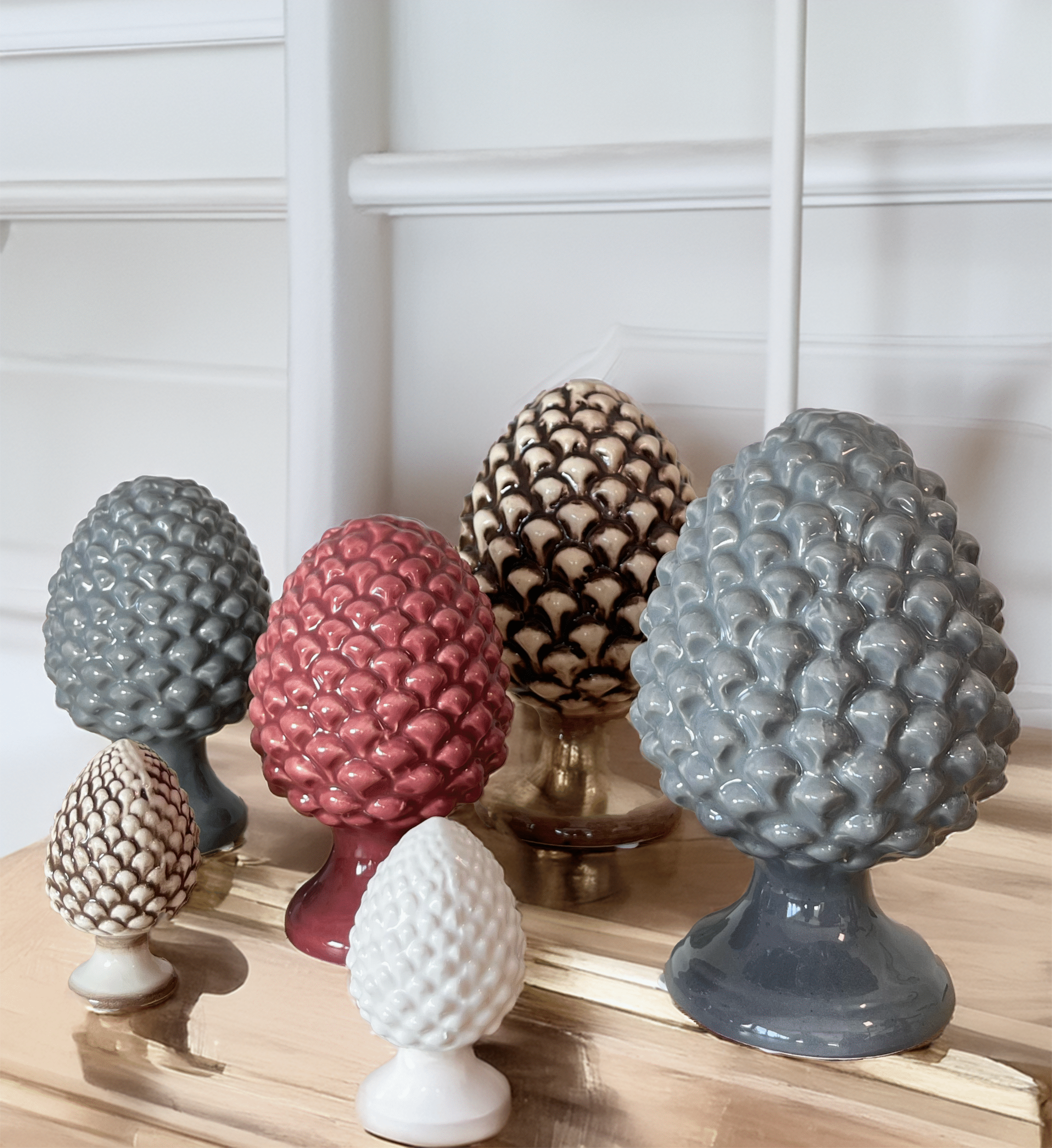 Présentation de plusieurs pommes de pins en céramique de différentes tailles et couleurs, objets typiques siciliens.