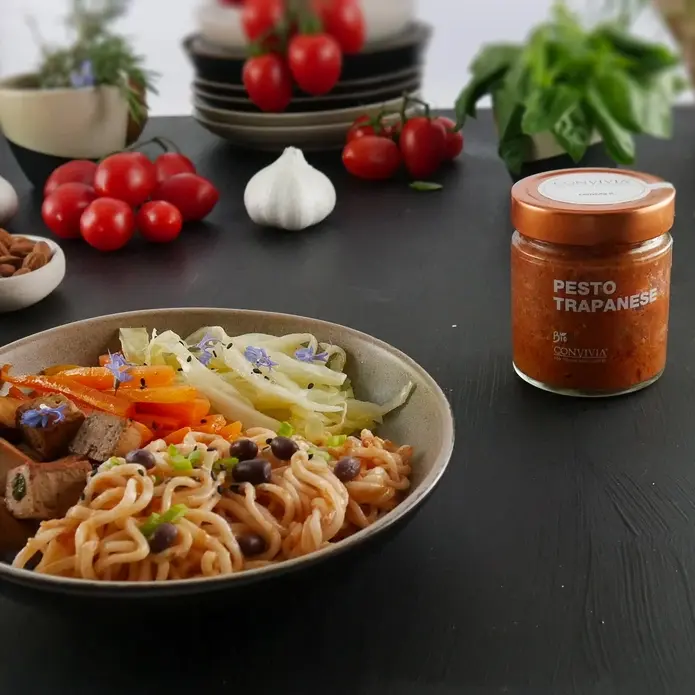 Pesto biologique à la trapanese de chez Convivia en Sicile, dans un pot en verre de 190g, avec un plat de pates.